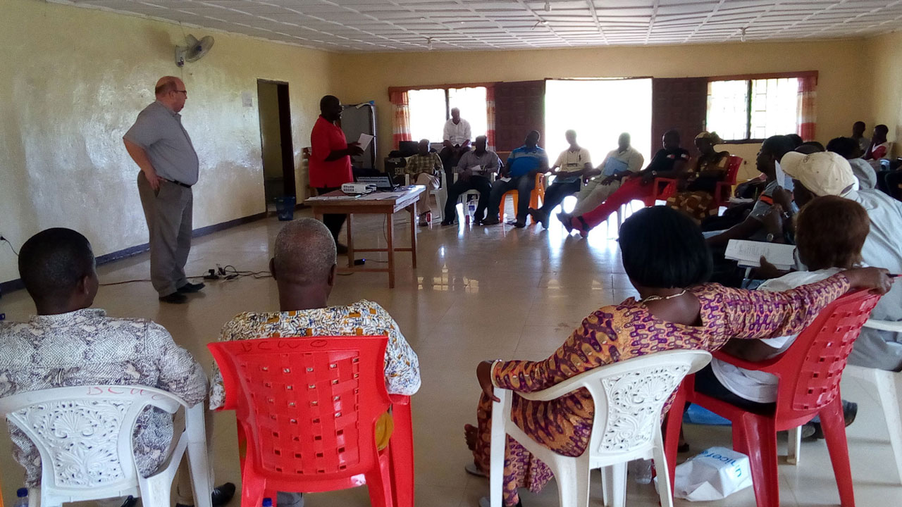 Training participants sit in semi-circle while trainers stand before them