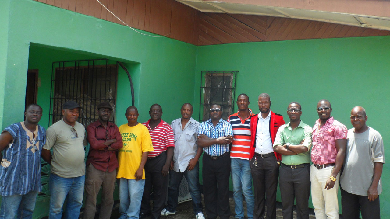 Group of men standing in front of a green building