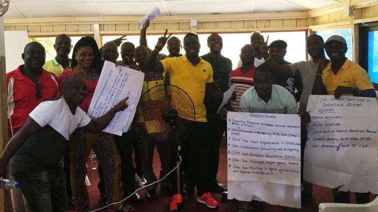 Participants posing and smiling at camera, some holding up poster paper with notes