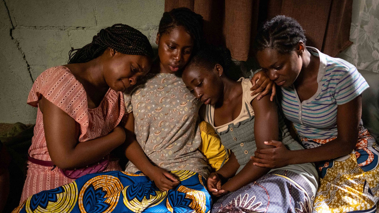 Four young women on the ground holding and consoling each other