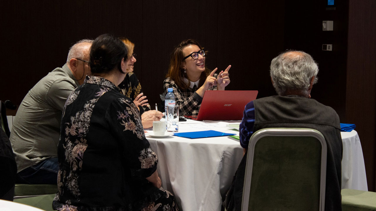 Participants sitting at a table and engaging in proposal writing workshop
