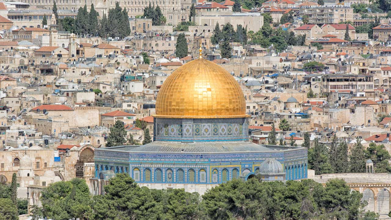 Dome of the gold color rock and city in the background.
