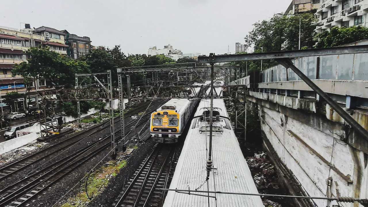 A yellow and white train on the tracks in an urban area