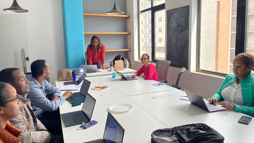 Six project team members sitting in around a conference table with laptops