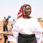 Woman wearing traditional outfit and smiling with hands open