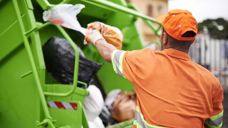 Sanitation worker putting trash into the trash truck