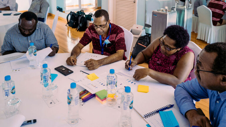 Training participants sitting at a table reading through training material